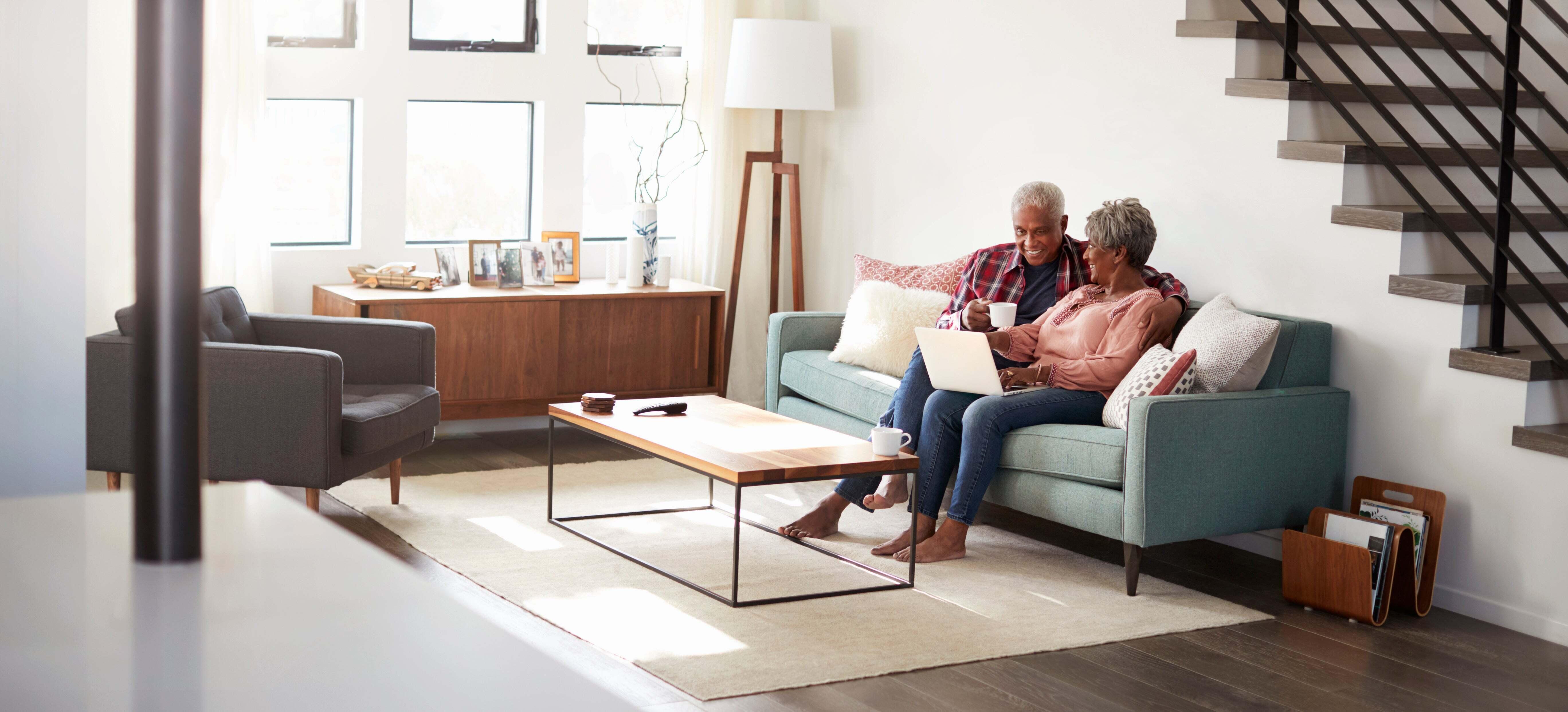 A couple sitting on a sofa with an area rug below their feet