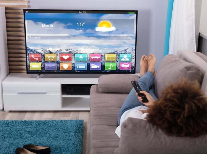 A person laying on a sofa watching a smart tv
