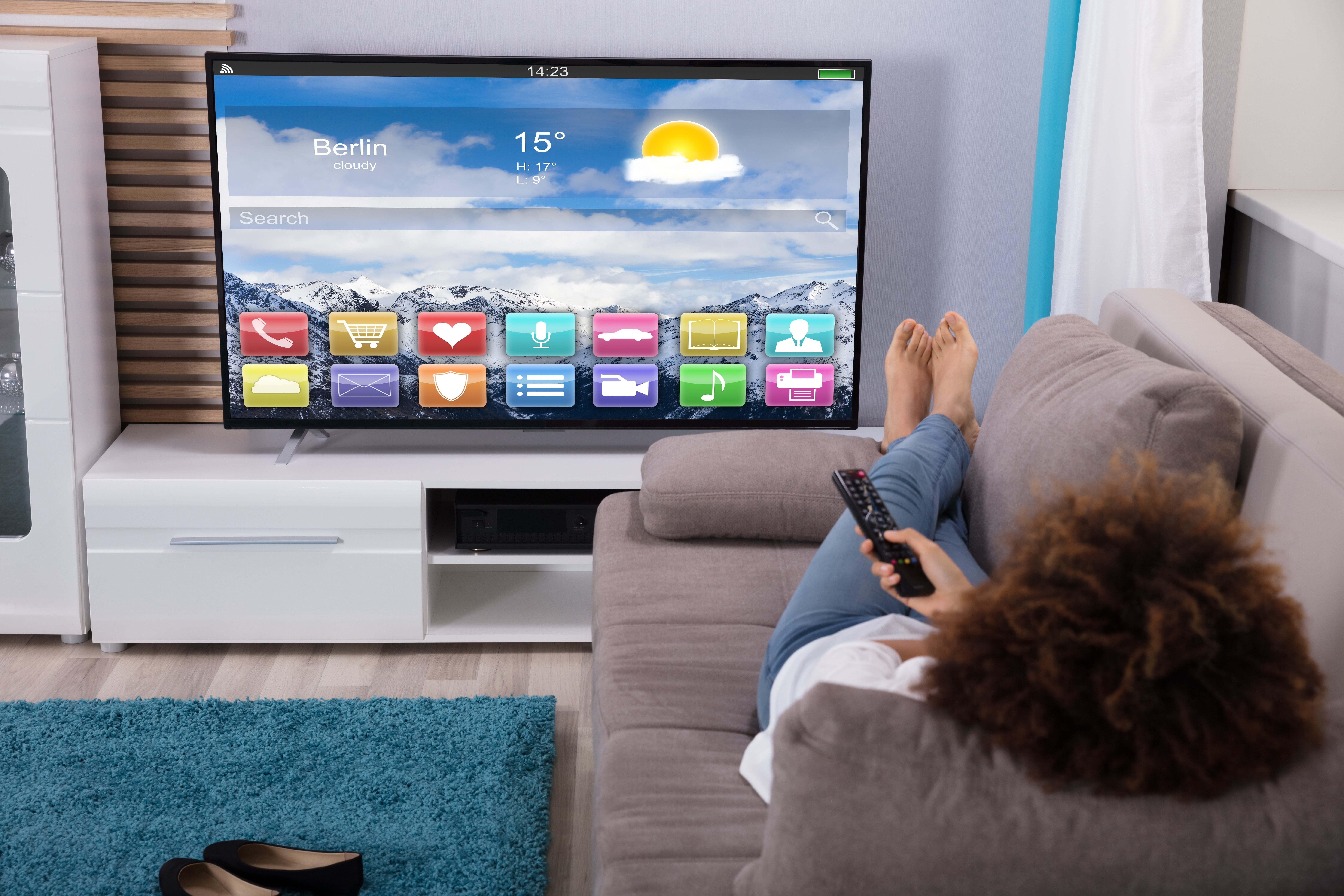 A person laying on a sofa watching a smart tv