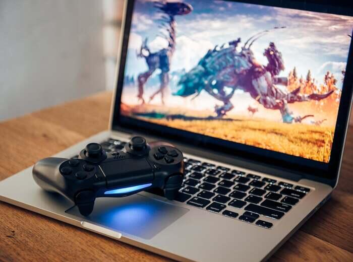 A gaming laptop with a game controller laying on it