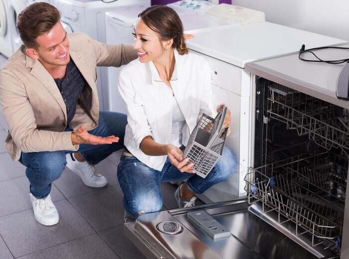 A salesman talking with a customer looking at dishwashers