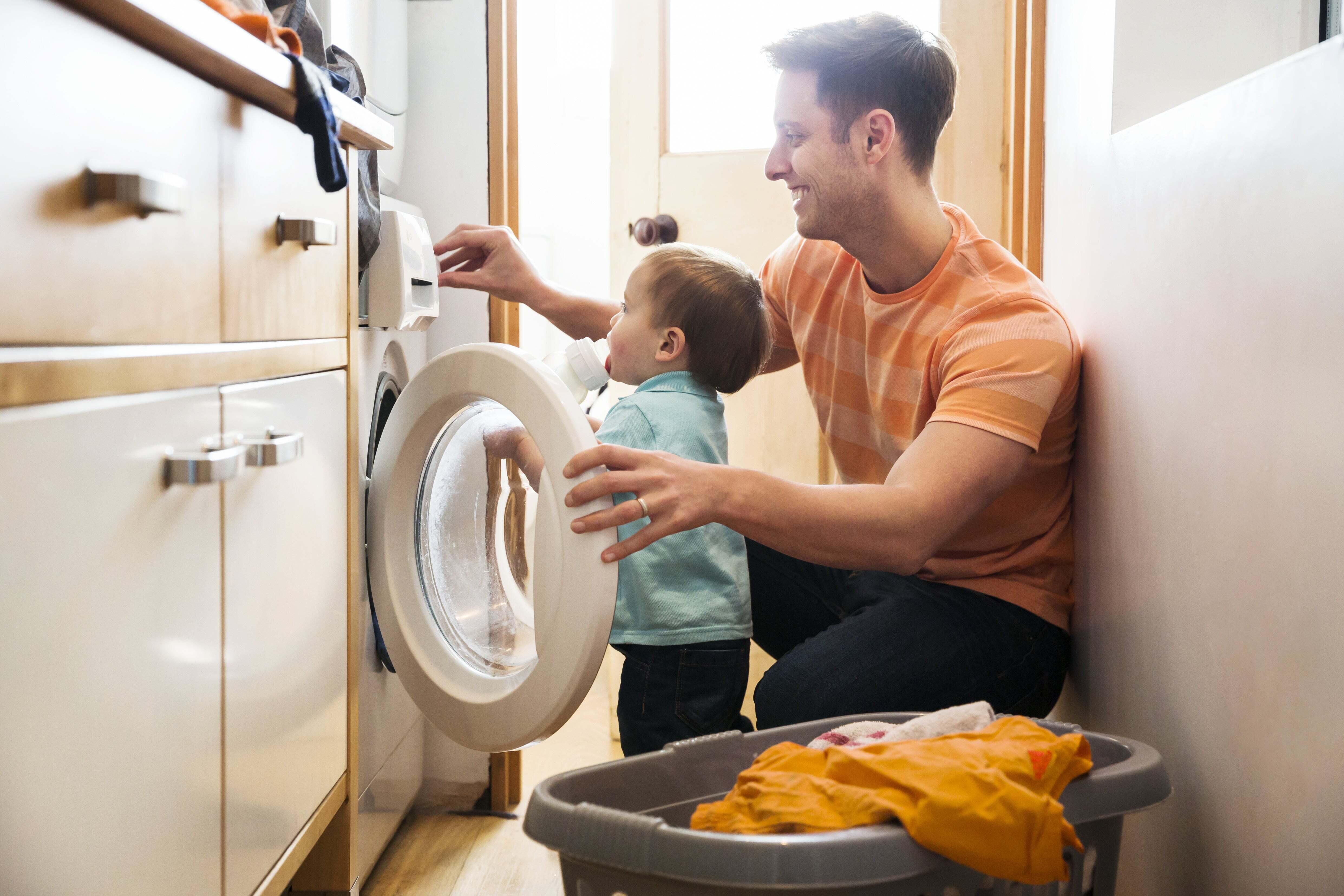 A father and son are loading a washing machine.