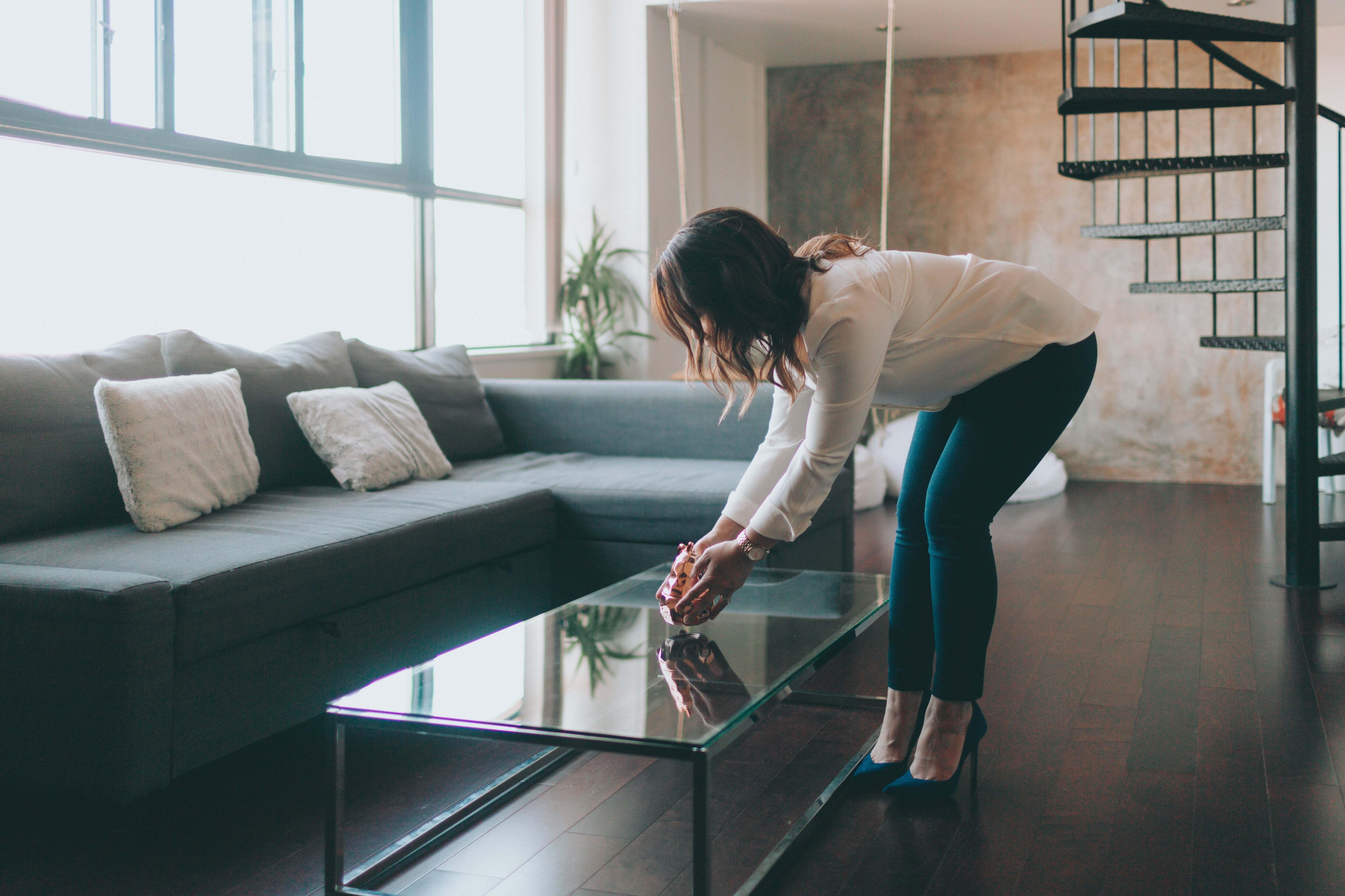 A woman placing a decoration on a glass table in her home