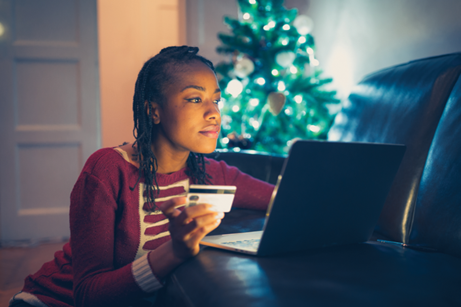 Young woman holding card while shopping on laptop